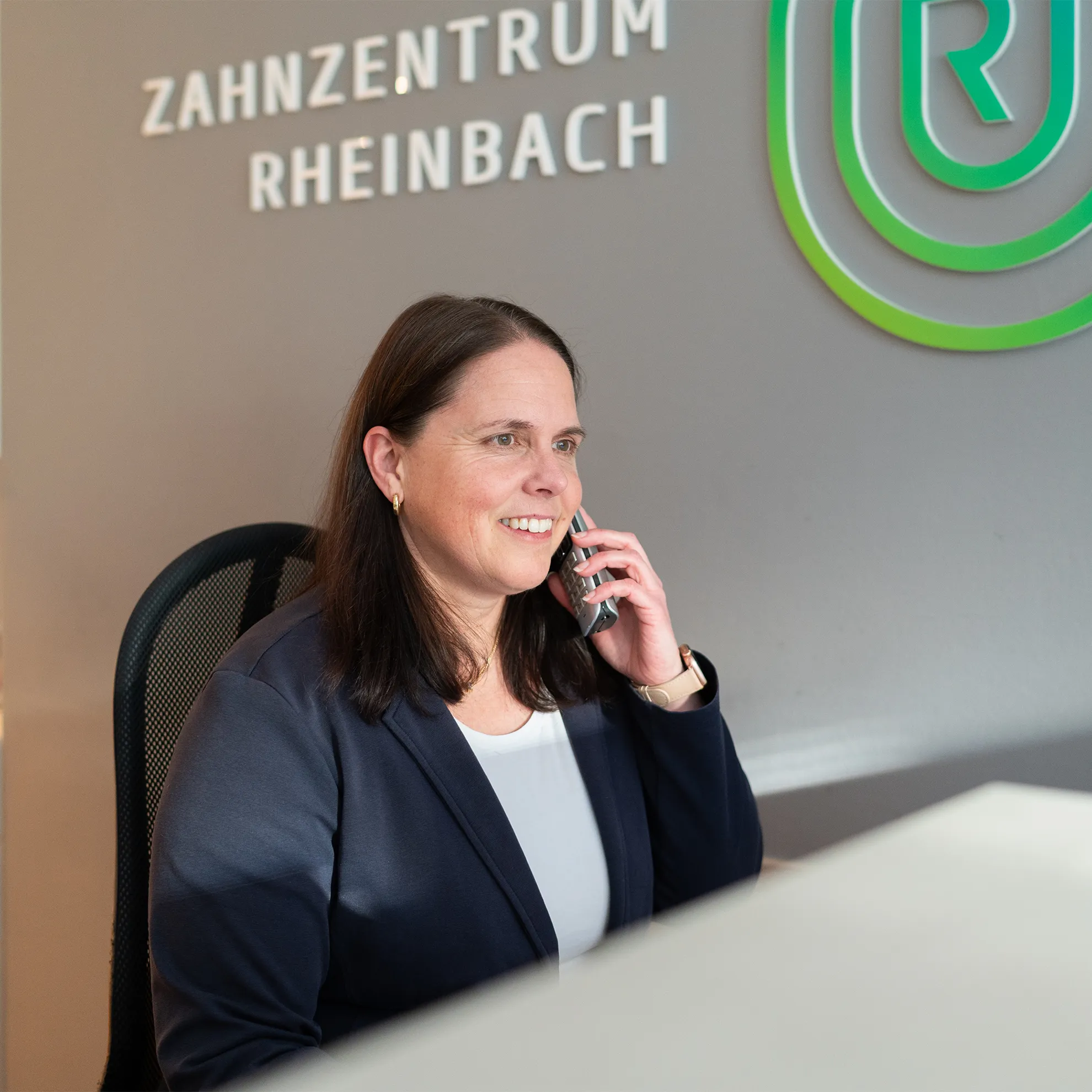 Eine Frau telefoniert und schaut lächelnd in den Bildschirm