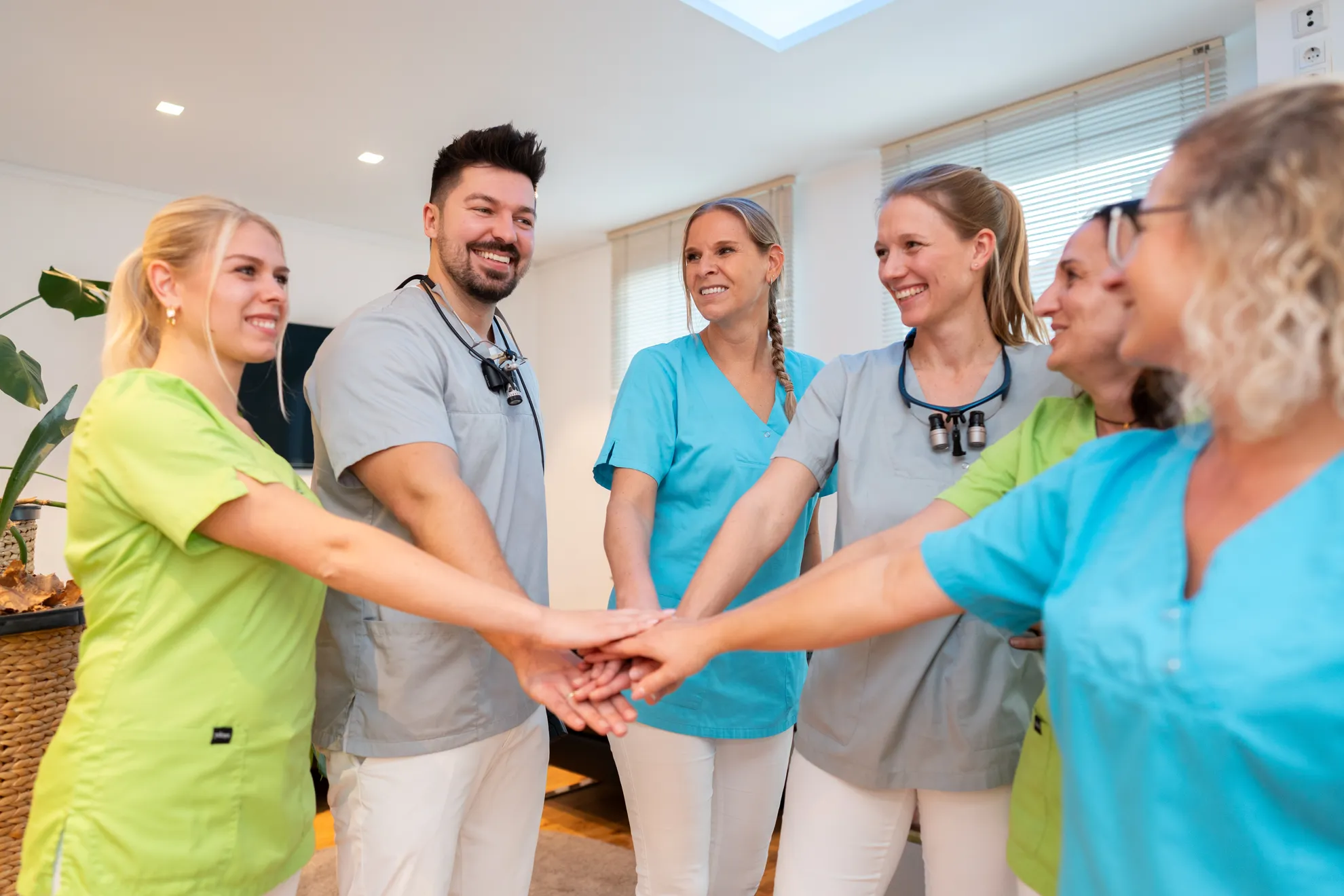 Das Team legt die Hände in der Mitte übereinander, als Zeichen von Teamgeist und Zusammenhalt