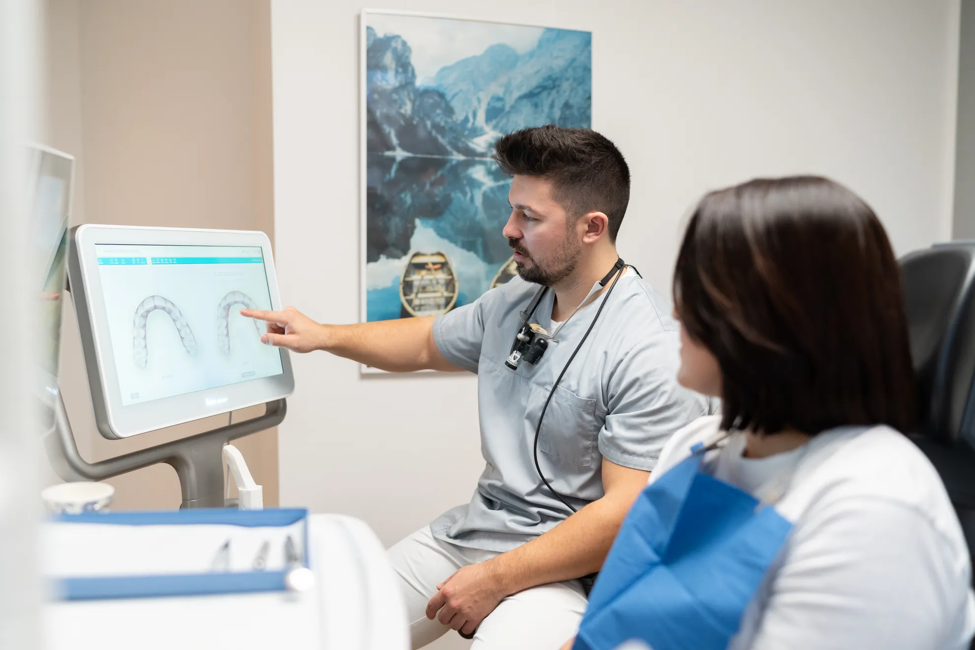 Zahnarzt zeigt Patientin etwas am Bildschirm